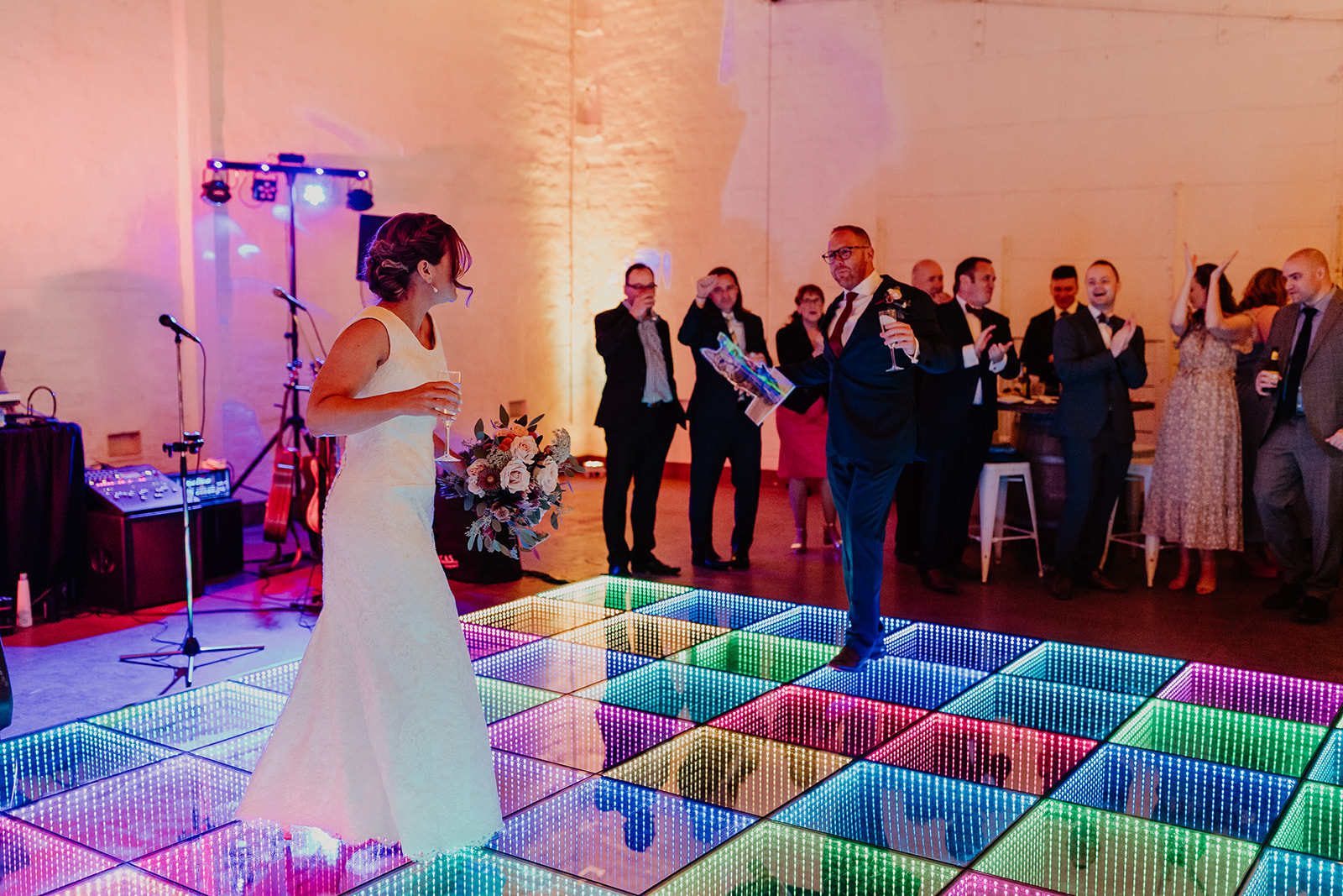 Bride and groom on the colourful LED dance floor as guests cheer
