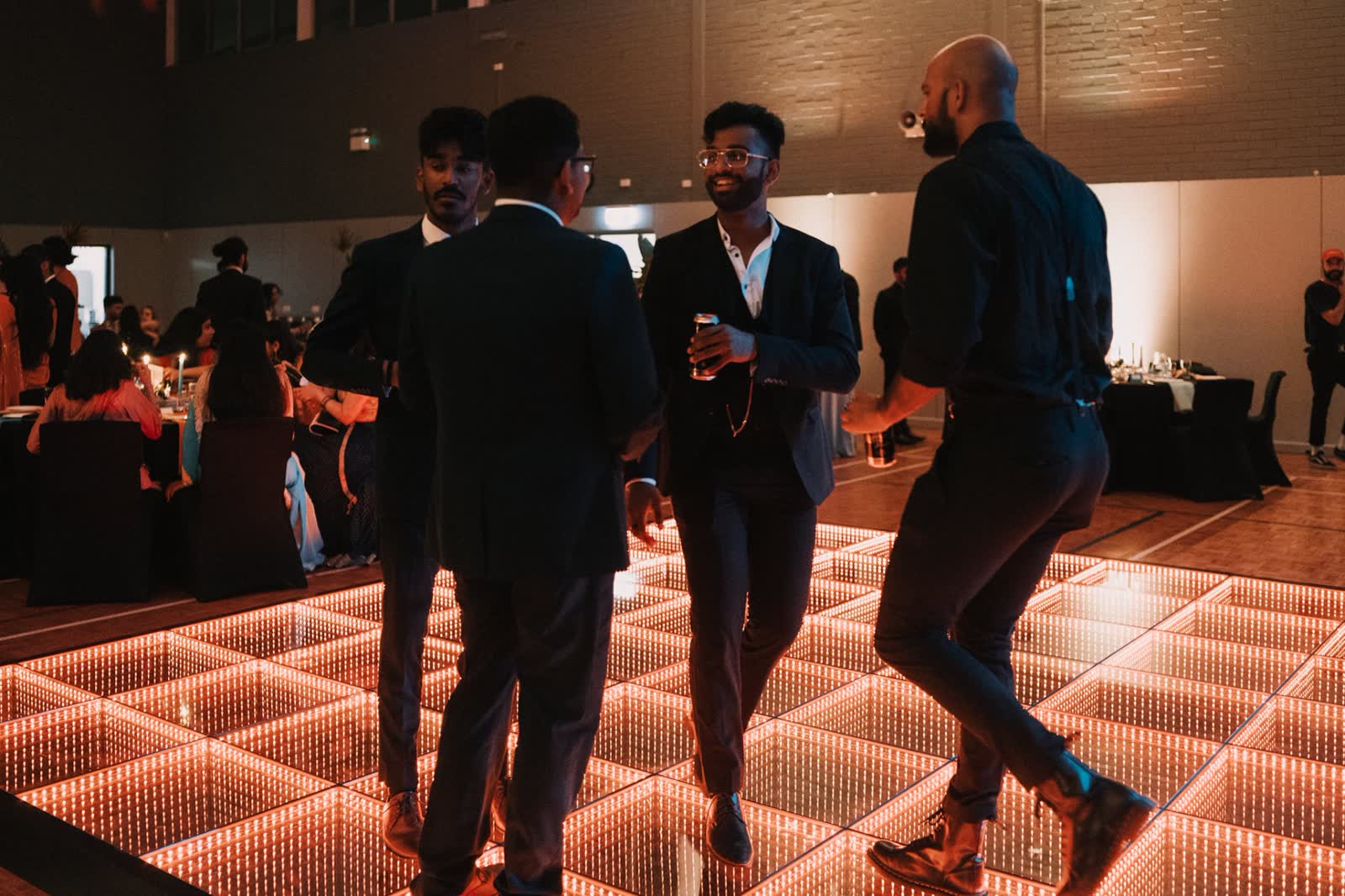 Guests dancing on the 3D infinity dance floor glowing warm orange at a Perth reception